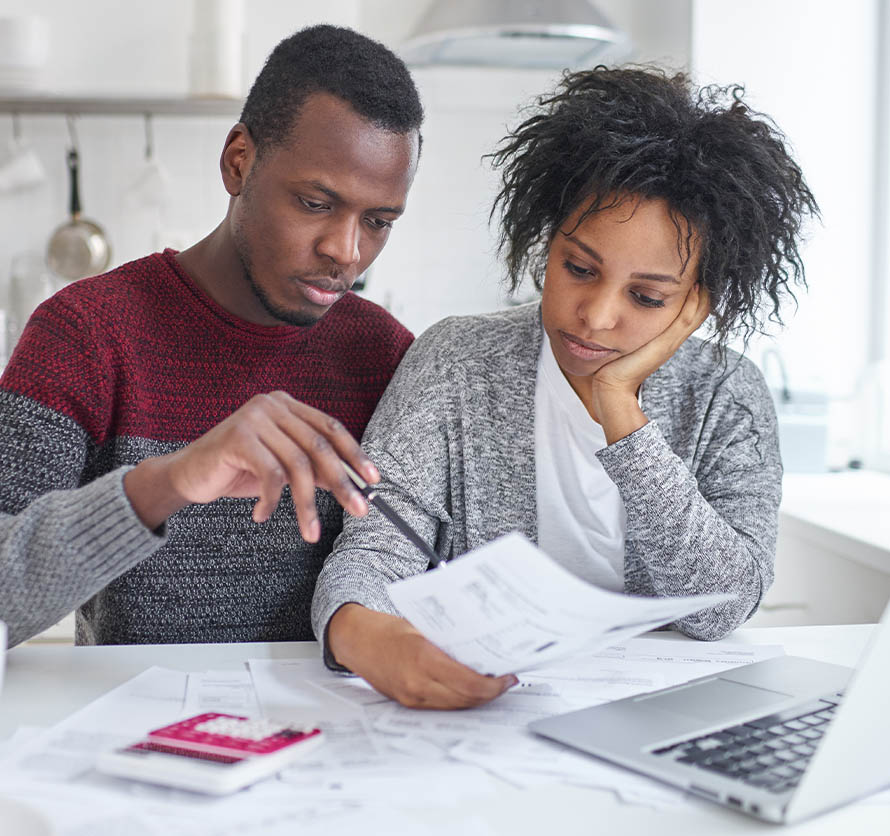 Young African American wife and husband sitting at home with laptop and bills preparing to file for chapter 13 bankruptcy